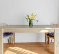 Jídelní stůl s květinovou vázou na podlaze s dřevěným dekorem v 2-pokojovém bytě.