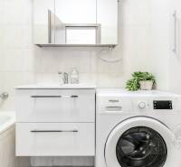 Koupelna s vanou, umyvadlem a pračkou v 2-pokojovém bytě.