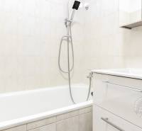 Koupelna s bílou vanou a umyvadlem v 2-pokojovém bytě.