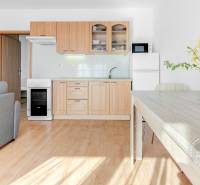 Kuchyně v 2-pokojovém bytě s podlahou s dřevěným dekorem a jídelním stolem.