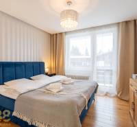 Ložnice v rekreačním apartmánu s pohodlnou postelí a podlahou s dřevěným dekorem.