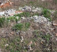 Pozemek na bydlení v Tešedíkově na ulici Tešedíkovo s neudržovanou vegetací a stavebním odpadem.
