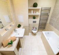 Koupelna v 2-pokojovém bytě s vanou, umyvadlem, zrcadlem a sušákem na ručníky.