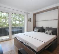 1-pokojový byt s výhledem na balkon a postelí ve chytré stěně.