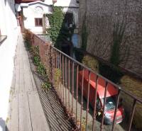 Úzký balkon s dřevěným dekorem nad dvorem a červenou dodávkou, Hlavní ulice, Prešov.