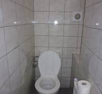 Toaleta v 3-pokojovém bytě s dlažbou a ventilačním otvorem.