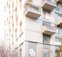 Bytový dům na Mlynských nivách v Bratislavě - Ružinově s balkony a rozkvetlými stromy.