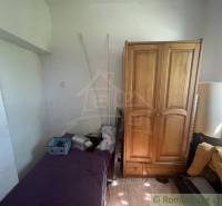 Pokoj v rodinném domě s postelí, dřevěnou skříní a oknem.