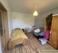 Pokoj v rodinném domě s postelí, stolem a podlahou s dřevěným dekorem.