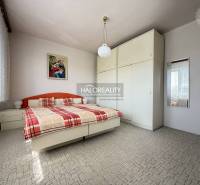 Ložnice v rodinném domě s velkou skříní, postelí a obrazem na stěně.