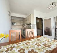 Jasná kuchyně v rodinném domě s dřevěným nábytkem a dekorativním stolním ubrusem.