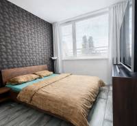 Ložnice v 2-pokojovém bytě s geometrickou tapetou a podlahou s dřevěným dekorem.