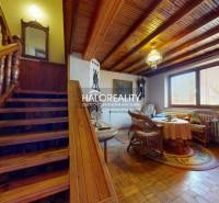 Interiér rodinného domu se schodištěm, podlahou s dřevěným dekorem a ratanovým nábytkem.