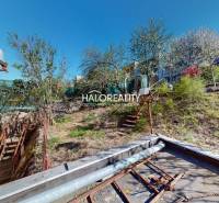 Rodinný dům v Rimavské Sobotě, vedle svažité zahrady se stromy.