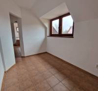 Interiér obchodních prostor s keramickou podlahou a šikmým stropem.