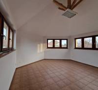 Interiér obchodních prostor s dlažbou a velkými okny, poskytující dostatek denního světla.