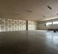 Výrobní prostory s vysokým stropem a betonovou podlahou.