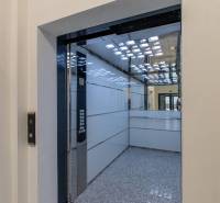 Interiér výtahu s nerezovými panely a zrcadlem, viditelná tlačítka.