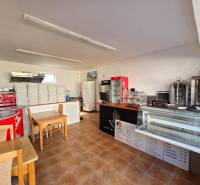 Interiér gastro prostor s pultem, chladicími vitrínami a stoh krabic na pizzu.