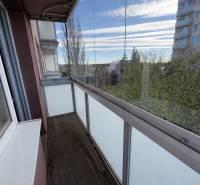Zasklený balkon s výhledem z 2-pokojového bytu, podlaha s dřevěným dekorem.