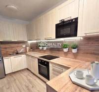 Moderní kuchyně v 2pokojovém bytě s dřevěným dekorem a vestavěnými spotřebiči.