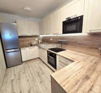 Kuchyně v 2-pokojovém bytě s podlahou s dřevěným dekorem a světlým nábytkem.