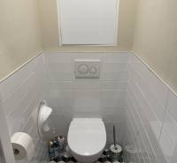 Toaleta ve 4-pokojovém bytě s geometrickou dlažbou a bílými obklady.