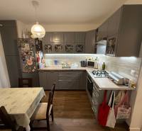 Kuchyně ve 4-pokojovém bytě s podlahou s dřevěným dekorem a rohovou kuchyňskou linkou.