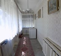 Interiér rodinného domu s chodbou, kobercem a záclonami na oknech.