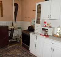 Kuchyně s bílými skříňkami a spotřebiči v rodinném domě.