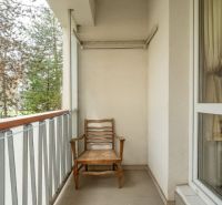 Balkon s dřevěnou židlí a zábradlím ve 4-pokojovém bytě.