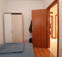 Ložnice v rodinném domě s postelí, šatní skříní a podlahou s dřevěným dekorem.