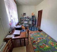Dětský pokoj s kobercem ve tvaru cesty, pracovním stolem a policovým regálem.