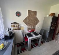 Kuchyně s jídelním stolem a podlahou s dřevěným dekorem ve 3-pokojovém bytě.