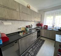 Kuchyně ve 3-pokojovém bytě se spotřebiči a podlahou s dřevěným dekorem.