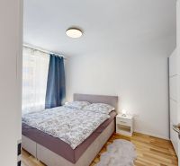Ložnice s manželskou postelí, nočním stolkem a podlahou s dřevěným dekorem v 2-pokojovém bytě.