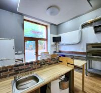 Interiér gastro prostorů s kuchyňským vybavením a podlahou s dřevěným dekorem.