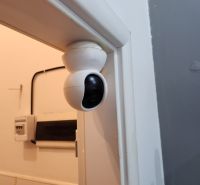 Bezpečnostní kamera na zdi v gastro prostorech, pod ní elektroinstalace.