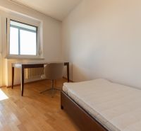 Pokoj s postelí, stolem a podlahou s dřevěným dekorem ve 4-pokojovém bytě.