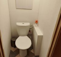 Toaleta v 1-pokojovém bytě s dlažbou a hygienickým příslušenstvím.