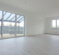 Prostorný interiér rodinného domu s velkými okny a podlahou s dřevěným dekorem.