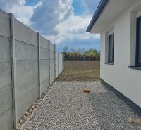 Rodinný dům v Selicích s betonovým plotem a štěrkovou dlažbou na dvoře.