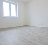 Prázdná místnost s bílými stěnami a podlahou s dřevěným dekorem v rodinném domě.