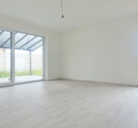 Prostorný pokoj s velkými okny a podlahou s dřevěným dekorem v rodinném domě.