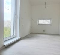 Interiér rodinného domu s podlahou s dřevěným dekorem a velkým oknem.