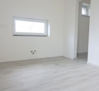Pokoj v rodinném domě s podlahou s dřevěným dekorem a malým oknem.