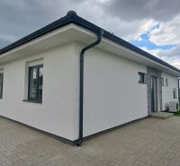 Rodinný dům v Topoľnici s bílou fasádou a dlážděnou terasou.