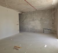 Nedokončená místnost v 3-pokojovém bytě s dráty visícími ze stropu.