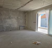 Nedokončený 3-pokojový byt s výhledem na terasu, nedokončené stěny a elektroinstalace.