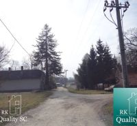 Venkovská cesta v lokalitě Starý přístav Gabčíkovo, obklopená dřevěnou architekturou a zelení. Pozemky - bydlení.